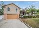 Charming two-story home boasts a tan exterior with a two-car garage and a landscaped front yard at 8425 Jackson Springs Rd, Tampa, FL 33615
