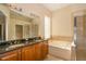 A bright bathroom with a double sink vanity, soaking tub and a separate glass shower stall at 1038 Emerald Dunes Dr, Sun City Center, FL 33573