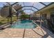Screened-in pool featuring a waterfall and lush landscaping, offering a serene backyard oasis at 1038 Emerald Dunes Dr, Sun City Center, FL 33573