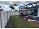 Landscaped backyard with green grass, white vinyl fence, and screened-in pool area at 1044 Manzanar Pl, Wesley Chapel, FL 33543