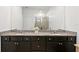 Bathroom featuring a double vanity with granite countertop, undermount sinks, and dark wood cabinets at 1044 Manzanar Pl, Wesley Chapel, FL 33543