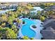 Aerial view showcasing a community pool with lush landscaping, shady trees, gazebo, and nearby walking trails by the lake at 1044 Manzanar Pl, Wesley Chapel, FL 33543