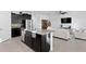 Open-concept kitchen featuring a large island, dark cabinetry, and a seamless flow into the living area at 1044 Manzanar Pl, Wesley Chapel, FL 33543