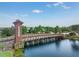 Community entrance with a decorative bridge over a pond, set against a backdrop of trees at 1044 Manzanar Pl, Wesley Chapel, FL 33543