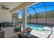 Relaxing screened-in pool area with stylish patio furniture and a view of the lush backyard at 1044 Manzanar Pl, Wesley Chapel, FL 33543