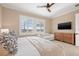Well-lit bedroom with a king-sized bed, a cozy sofa, and a wooden dresser beneath the wall-mounted television at 1110 Overlook Ct, Bradenton, FL 34208