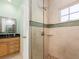 Tiled shower with glass door, wood cabinets, and dark granite countertop, accented with a window at 1140 81St S St, St Petersburg, FL 33707