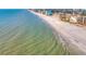 Scenic aerial view of shoreline on a sunny day with clear blue water and coastal town in the distance at 12924 Gulf Blvd # 310, Madeira Beach, FL 33708