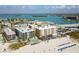 Aerial view showcases beachfront condos, a bridge, and stunning views of the coastline and waterways at 12924 Gulf Blvd # 310, Madeira Beach, FL 33708