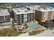 Aerial view of a beachfront complex with a pool and ocean views; a great vacation spot at 12924 Gulf Blvd # 310, Madeira Beach, FL 33708