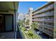 Balcony view overlooking a grassy lawn, palm trees, parking area, and multiple-story condominium building at 12924 Gulf Blvd # 310, Madeira Beach, FL 33708