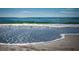 Serene beach view with gentle waves meeting the shore and glistening in the sunlight at 12924 Gulf Blvd # 310, Madeira Beach, FL 33708