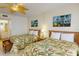 Comfortable bedroom featuring two beds with floral patterns and island-themed wall art at 12924 Gulf Blvd # 310, Madeira Beach, FL 33708
