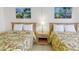 Bedroom featuring two beds with floral patterns, side table and island-themed wall art at 12924 Gulf Blvd # 310, Madeira Beach, FL 33708