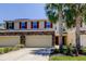Inviting townhome with tan exterior, stone accents, two-car garage, and beautiful landscaping with palm trees at 13217 Canopy Creek Dr, Tampa, FL 33625