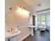 Bathroom featuring double sinks, mirrors, and a classic soaking tub at 14807 Capps Estates Ln, Wimauma, FL 33598
