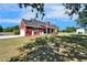 Exterior view of red house with black roof, attached garage, covered porch, and lush green lawn at 14807 Capps Estates Ln, Wimauma, FL 33598