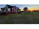 Charming two-story home with a manicured lawn and garden beds, set against a beautiful sunset backdrop at 14807 Capps Estates Ln, Wimauma, FL 33598