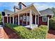 Expansive front porch of the red house featuring classic columns, arched windows and well-maintained landscaping at 14807 Capps Estates Ln, Wimauma, FL 33598
