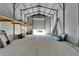 Interior of a metal garage with a concrete floor, open door, and an overhead storage platform at 14807 Capps Estates Ln, Wimauma, FL 33598