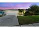 Charming single-story home at twilight with a well-manicured lawn, mature trees, and a two car garage at 15018 Greeley Dr, Tampa, FL 33625