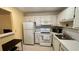 View of the kitchen features white cabinets and a suite of white appliances and lots of counter space at 1801 Bedford Ln # 46, Sun City Center, FL 33573