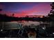 Serene backyard view featuring a waterfront view, a fire pit, rocking chairs, and a pink sky at 21832 Crest Meadow Dr, Land O Lakes, FL 34637