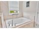 Bathroom featuring a large soaking tub, neutral tiling and large window with a view at 21832 Crest Meadow Dr, Land O Lakes, FL 34637