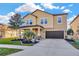Two-story home with tan exterior, dark garage, landscaped front yard, and beautiful lawn at 21832 Crest Meadow Dr, Land O Lakes, FL 34637