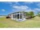Exterior of sun room and large lawn with side view of home and manicured landscaping at 2401 Richmond Greens Ct, Sun City Center, FL 33573