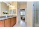 Bathroom showcasing granite counters, wood cabinets, double sinks, and a glass-enclosed shower at 2401 Richmond Greens Ct, Sun City Center, FL 33573