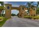 Attractive community entrance with ornate archway, lush landscaping, and a security booth at 2401 Richmond Greens Ct, Sun City Center, FL 33573