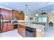 Open-concept kitchen with island, granite countertops, wooden cabinets, and stainless steel appliances at 2401 Richmond Greens Ct, Sun City Center, FL 33573