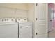 A laundry room features a white washer and dryer with wire shelving above them at 2949 Suncoast Plains Dr, Odessa, FL 33556