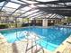Community pool featuring a screened-in enclosure, crystal-clear water, and a nearby clubhouse and chairs at 3358 Mermoor Dr # 2106, Palm Harbor, FL 34685