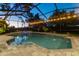 Sparkling screened-in pool with luxurious tilework, ambient lighting, and lush tropical landscaping at 3612 Sugar Loaf Ln, Valrico, FL 33596