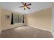 Bedroom featuring a ceiling fan, neutral carpeting, and a window with black curtains at 5714 Kingletsound Pl, Lithia, FL 33547