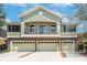 Two story home featuring a balcony, light green stucco, stone accents, and a three car garage at 5714 Kingletsound Pl, Lithia, FL 33547