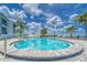 Community swimming pool with brick border, metal railing, surrounded by chairs and palm trees, under a partly cloudy sky at 803 Bahia Del Sol Dr # 66, Ruskin, FL 33570