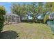 The backyard has a large grassy area, lush plants, and a screened in patio at 8847 Bel Meadow Way, Trinity, FL 34655