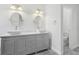 Bright bathroom with a dual sink vanity, oval mirrors, and gray cabinets at 8847 Bel Meadow Way, Trinity, FL 34655