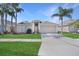 Charming single-story home with a two-car garage, well-manicured lawn, and tropical palm trees enhancing its curb appeal at 10275 Oasis Palm Dr, Tampa, FL 33615