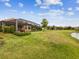 Well-manicured backyard featuring a screened lanai, lush lawn, and view of the pond at 11248 Juglans Dr, Odessa, FL 33556
