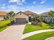Exterior view of the single-story home with a tile roof, paver driveway, and lush landscaping at 11248 Juglans Dr, Odessa, FL 33556