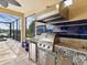 The outdoor kitchen has stainless steel appliances, stone counters, blue backsplash and a hood vent at 11248 Juglans Dr, Odessa, FL 33556
