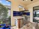 Outdoor kitchen featuring a stainless steel grill, stone counters, blue backsplash and beverage refrigerator at 11248 Juglans Dr, Odessa, FL 33556