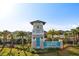 Lucaya Lake Club entrance featuring a decorative tower, lush landscaping, and clear blue skies at 11327 Emerald Shore Dr, Riverview, FL 33579
