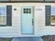 Close up of the entry way with a stylish light blue front door with black hardware and adjacent window shutters at 1209 W Camellia Dr, Brandon, FL 33510