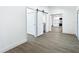 Open-concept living area with wood-look floors, white walls, sliding barn door, and kitchen view at 1209 W Camellia Dr, Brandon, FL 33510