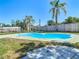 Backyard in-ground pool is surrounded by palms, a wood fence and concrete decking under a clear blue sky at 1209 W Camellia Dr, Brandon, FL 33510